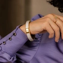 Sztywna, złota bransoletka ozdobiona białą skórką. KLASA W SOBIE