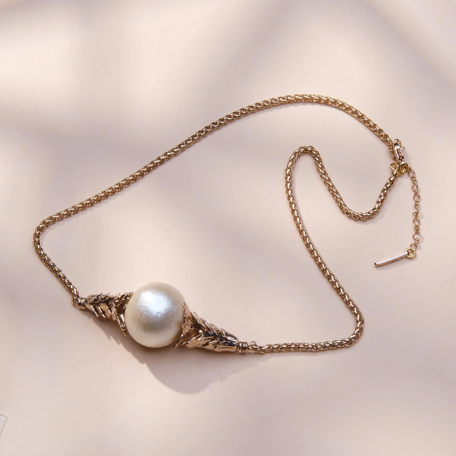 Złocony naszyjnik z perłą bawełnianą w objęciu liści. BON TON W MENTON