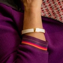 Sztywna, złota bransoletka ozdobiona białą skórką. KLASA W SOBIE