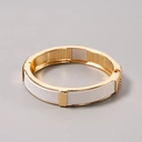 Sztywna, złota bransoletka ozdobiona białą skórką. KLASA W SOBIE