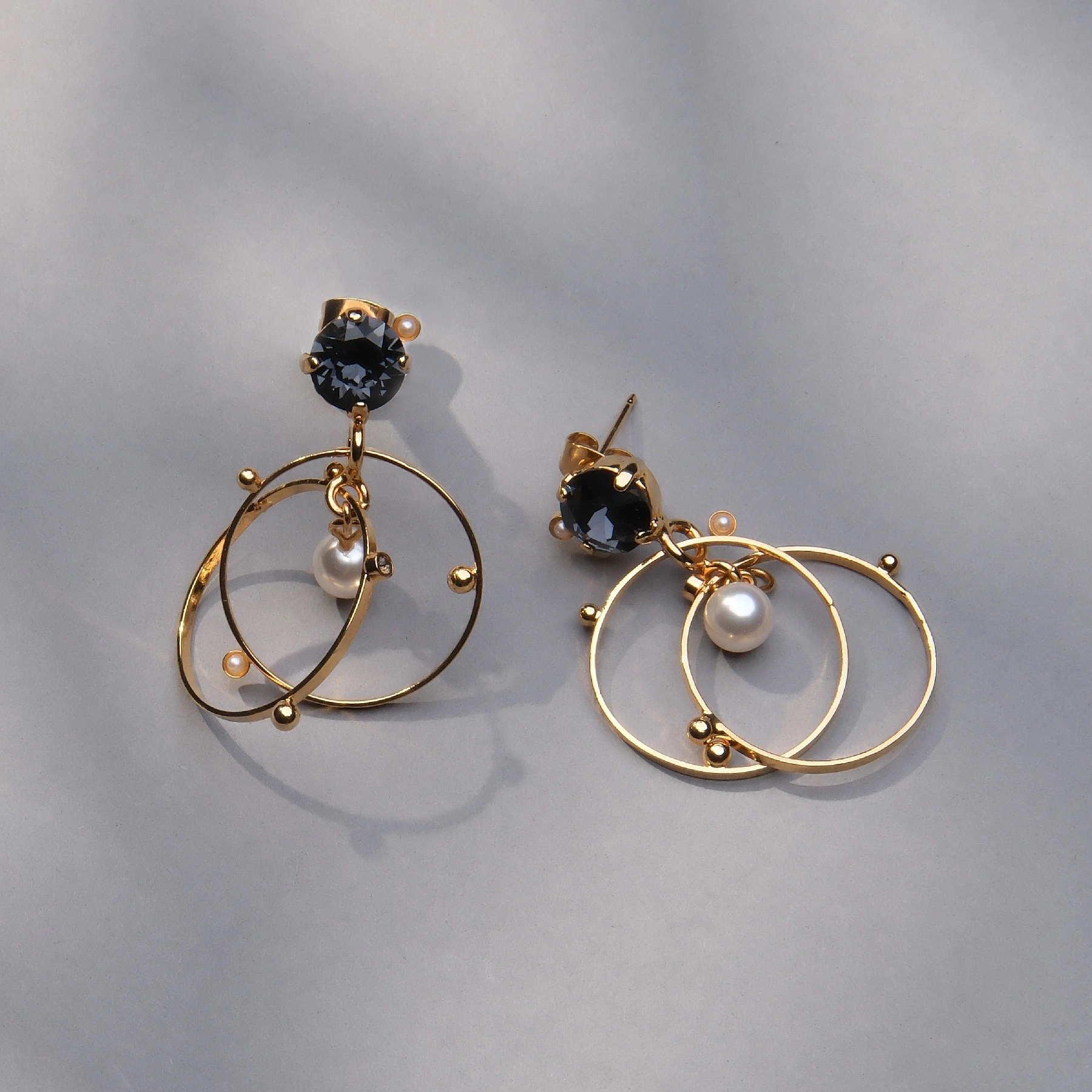 Pozłacane kolczyki koła z granatowym kryształem i perłą. BIAŁY ŁABĘDŹ