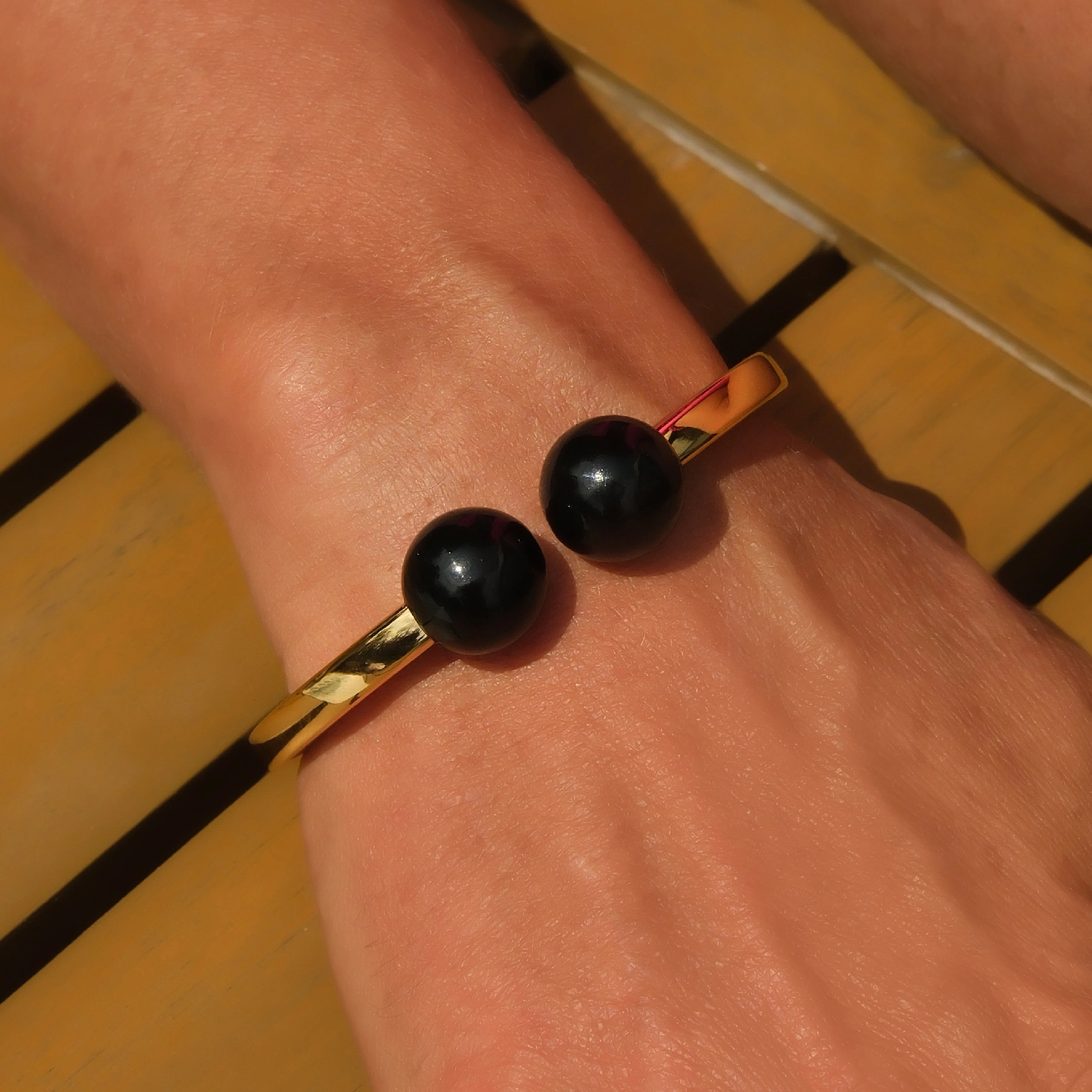 Sztywna otwarta bransoleta z lekkimi czarnymi kulami. DLA KOBIETY BIZNESU