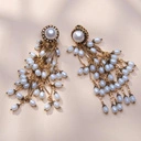 Kolczyki z dużą perłą na bazie i małymi na zawieszce. SEGRETO