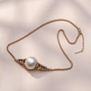 Złocony naszyjnik z perłowym koralikiem w objęciu liści. BON TON W MENTON