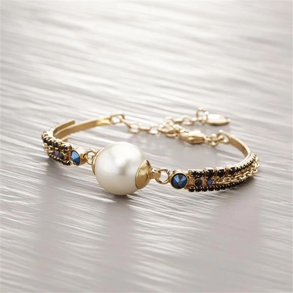 Złota bransoletka z perłową kulą i kryształkami. DUCHAMP