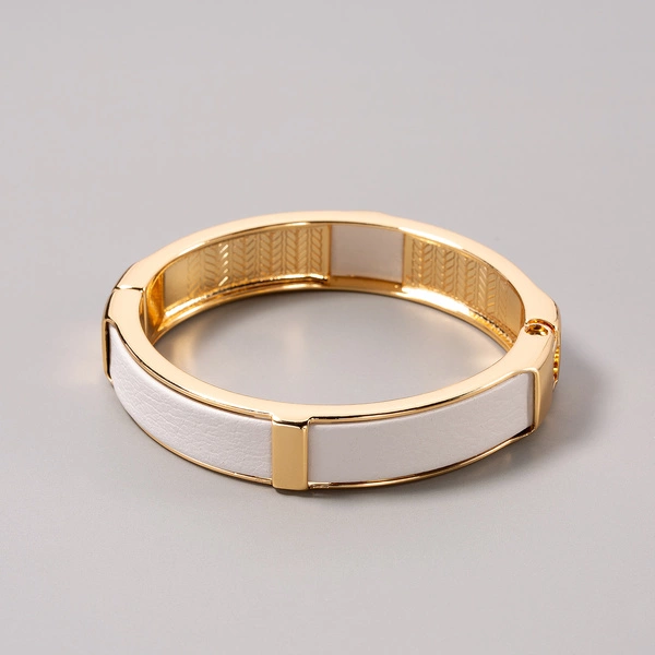 Sztywna, złota bransoletka ozdobiona białą skórką. KLASA W SOBIE