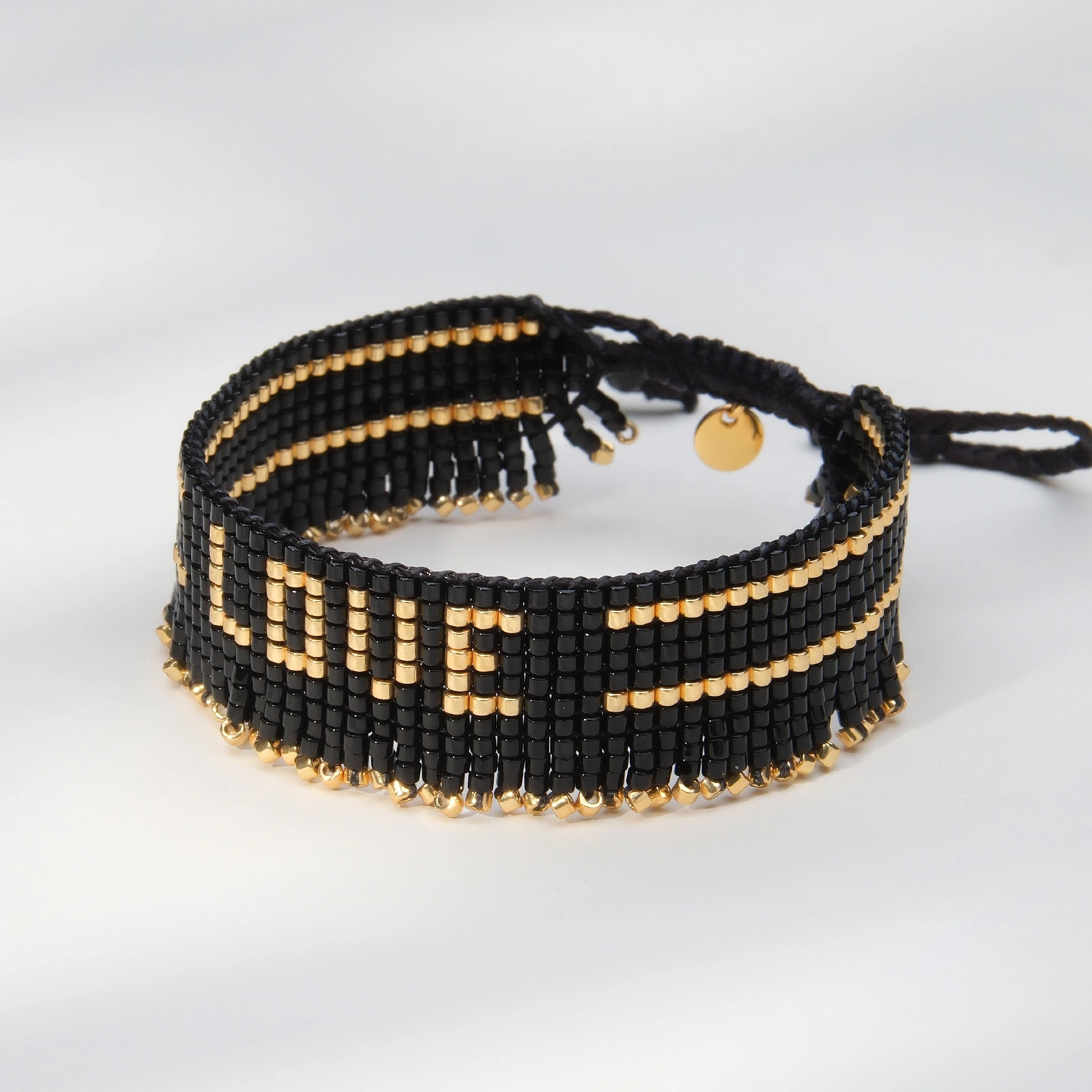 Bransoletka z czarnych paciorków Miyuki ze złotym napisem. CZUŁOŚCI W CIEMNOŚCI