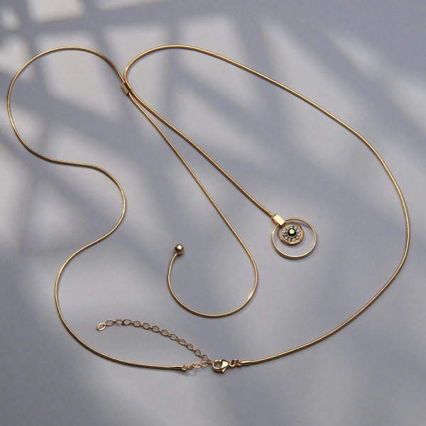 Złocony naszyjnik na żmijce z zielonym i białymi kryształami. STAŁA GRAWITACJI