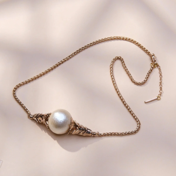 Złocony naszyjnik z perłowym koralikiem w objęciu liści. BON TON W MENTON